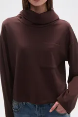 Buzo negro de manga larga con cuello alto tipo chimenea y un bolsillo cuadrado en el pecho.