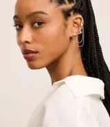 Ear cuff dorado asimétrico con caravana y cadenas colgantes, y caravana pequeña con forma de flor.