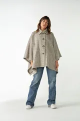 Capa con cuello, cierre frontal con botones y bolsillos delanteros. Confeccionada en lana fina sin teñir, diseñada exclusivamente por Don Baez.