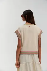 Top tejido de punto color crudo, con cuello redondo y mangas cortas con terminaciones acanaladas a rayas de colores.