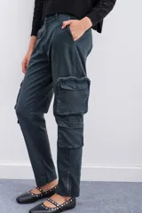 Pantalón cargo color verde oscuro, de corte recto y tiro medio, con ajuste en los tobillos. Confeccionado en gabardina elastizada, cuenta con un cinturón interno y hebilla marcaria que permiten ajustar la cintura. Tiene 2 bolsillos en cada lateral y cierres metálicos en la botamanga.