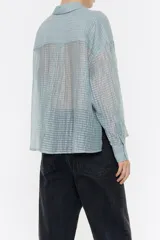 Camisa rosa con rayas horizontales, de corte holgado, manga larga con puños abotonados, cuello camisero, cierre frontal con botones, bolsillo de parche en el pecho y canesú en la espalda con pliegue.