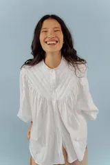 Camisa blanca de algodón con cuello mao, mangas largas abullonadas y costuras frontales.
