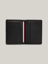 Billetera plegable Tommy Hilfiger de cuero negro con sutil acabado granulado. Presenta costuras distintivas en rojo, blanco y azul en el frente y logo de la marca en la parte inferior.