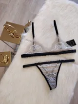 Conjunto de lencería color tostado con detalles en negro, compuesto por un corpiño triangular de encaje con breteles finos y una tanga de encaje con tiras laterales ajustables.