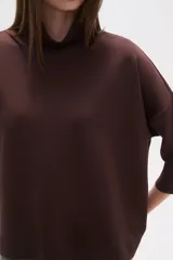 Polera holgada de poliéster color verde militar, con cuello alto tipo tortuga y mangas tres cuartos.