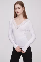 Remera blanca de manga larga con escote en V y detalle de encaje en el pecho.
