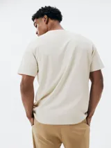 Remera color beige de algodón con bolsillo en el pecho y bordado de montañas.