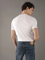 Remera blanca de algodón con cuello redondo y mangas cortas. Estampado frontal con el logo "Calvin Klein Jeans" en color negro.