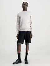 Sweater color beige de Calvin Klein, confeccionado en mezcla de tencel con elasticidad añadida. Tiene cuello redondo, puños y bajo de canalé, y etiqueta con logo de Calvin Klein por encima del bajo.