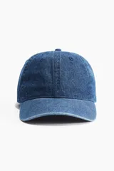 Gorra de denim azul con ojales bordados en la parte superior, trabilla ajustable con hebilla de metal en la parte trasera y cinta antitranspirante de algodón.