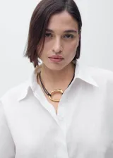 Camisa blanca de manga corta confeccionada en mezcla de algodón y lino, con cierre frontal de botones, cuello camisero y corte recto.