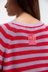 Sweater de punto a rayas horizontales rojas y lilas, de corte recto y mangas largas.