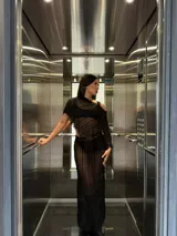 Poncho tejido de red color negro, con terminaciones desflecadas y diseño asimétrico.