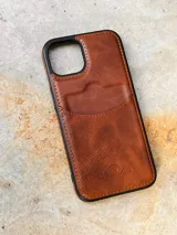 Funda de cuero marrón para iPhone con tarjetero en la parte posterior y logo de la marca Sierra Mora grabado en la parte inferior.