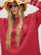 Sweater color crema con tejido en ochos, cuello redondo, puños acanalados con doble raya azul y tajos a los costados.