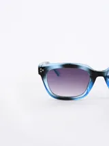 Lentes de sol con montura celeste marmolada y lentes degradé de gris a violeta.