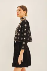 Saco corto negro, ajustado al cuerpo, con escote redondo y bordado a mano en frente, espalda y mangas con lentejuelas y pedrería en forma de estrellas y motivos florales.