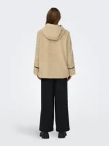 Abrigo de tela tipo teddy color beige, con capucha, cierre con botones tipo duffle coat y bolsillos frontales. Detalles en cuero sintético negro en los bordes y en los botones.