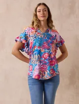 Blusa estampada con motivos florales en tonos rosa, azul y naranja. Tiene cuello en V y mangas cortas con volados.