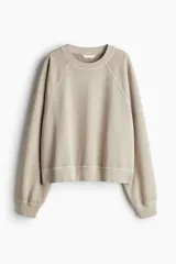 Buzo color beige de algodón con efecto lavado, corte oversized, mangas raglán y cuello, puños y bajo en punto acanalado.