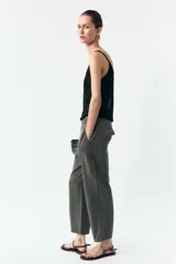 Pantalón gris oscuro de tiro alto con cintura elástica, bolsillos delanteros y falsos bolsillos con solapa en la espalda. Cierre frontal con cremallera y botón.