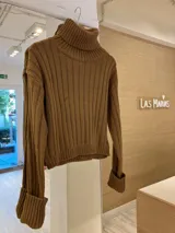 Sweater de punto color verde oliva, con cuello alto y mangas largas con puños acanalados.