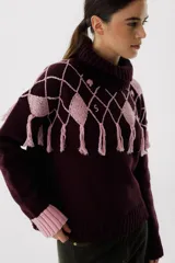 Sweater tejido de punto color crudo con cuello alto y diseño de rombos marrones con flecos.