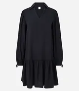 Vestido corto negro de viscosa con cuello en V, mangas largas abullonadas con lazo en los puños y falda con volantes.