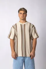 Remera de tejido de punto color crudo con rayas verticales marrones y negras, de manga corta y corte recto.