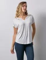 Blusa blanca de modal con cuello redondo y escote en V. Tiene apliques de crochet en el escote y los hombros.