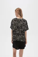 Blusa verde militar con estampado de flores blancas, de viscosa, corte holgado, cuello redondo y mangas cortas.