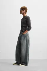 Pantalón de jean negro de corte amplio, con cinco bolsillos, efecto lavado y cierre frontal con cremallera y botón.