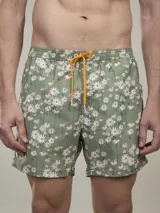 Short de baño verde con estampado de margaritas blancas y cordón ajustable naranja.