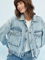 Campera de jean celeste con efecto lavado, corte cropped, cuello clásico, cierre frontal con botones metálicos, cuatro bolsillos frontales con solapa y puños abotonados.