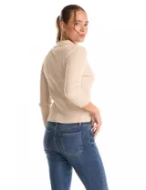 Buzo de punto acanalado color beige, con cuello polo y cierre de botones en el escote. Manga tres cuartos.