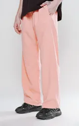 Pantalón de corte sastrero color salmón, de tela suede suave y holgada, con bolsillos laterales, cintura trasera elástica ajustable y cierre frontal con botón.