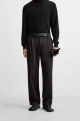 Pantalón negro de corte recto con cinturón de cuero sintético, pliegues frontales, bolsillos laterales y traseros con solapa.