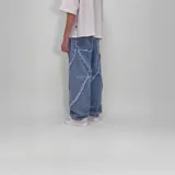 Pantalón de jean celeste, corte ancho y diseño de líneas cruzadas con flecos en el frente.