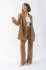 Blazer marrón de pana con solapas de muesca, cierre frontal con dos botones, bolsillos con solapa y corte holgado.