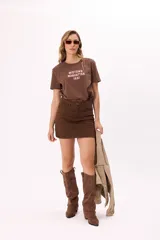 Minifalda color ocre de denim con corte recto, tiro medio y detalle de tachas metálicas en los laterales.