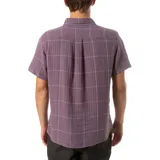 Camisa violeta a cuadros blancos, de manga corta y corte recto. Tiene cuello clásico, cierre con botones y bolsillo en el pecho.