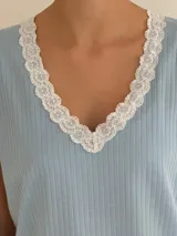 Conjunto de pijama de dos piezas color negro, compuesto por una remera de manga corta con escote en V adornado con puntilla beige, y un short con lazo frontal beige y terminación de puntilla beige en el ruedo.