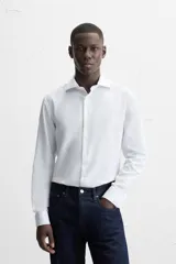 Camisa blanca de corte regular, cuello italiano, manga larga con puños abotonados y cierre frontal con botones.