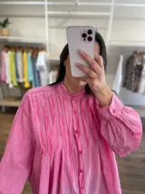 Camisa azul de algodón, corte amplio, con cuello mao, mangas largas con puños abotonados y cierre frontal con botones.