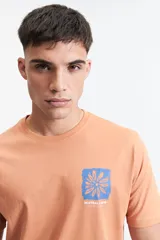 Remera color salmón de manga corta con cuello redondo y estampado en el pecho.