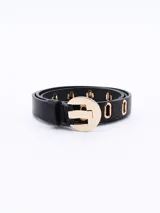 Cinto negro de cuero sintético con hebilla circular dorada y perforaciones con forma de letra 'O'.