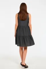 Vestido gris de algodón, largo hasta la rodilla, con cuello camisero, sin mangas, cierre frontal de botones blancos y falda con volados.