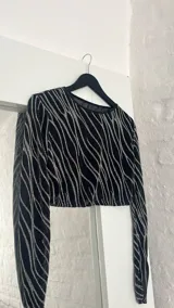 Conjunto de top manga larga y minifalda con estampado de líneas brillantes sobre tela transparente negra.