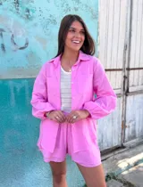 Conjunto de lino color rosado, compuesto por una camisa de manga larga con cuello clásico y botones frontales, y un short con bolsillos laterales y forro interno.